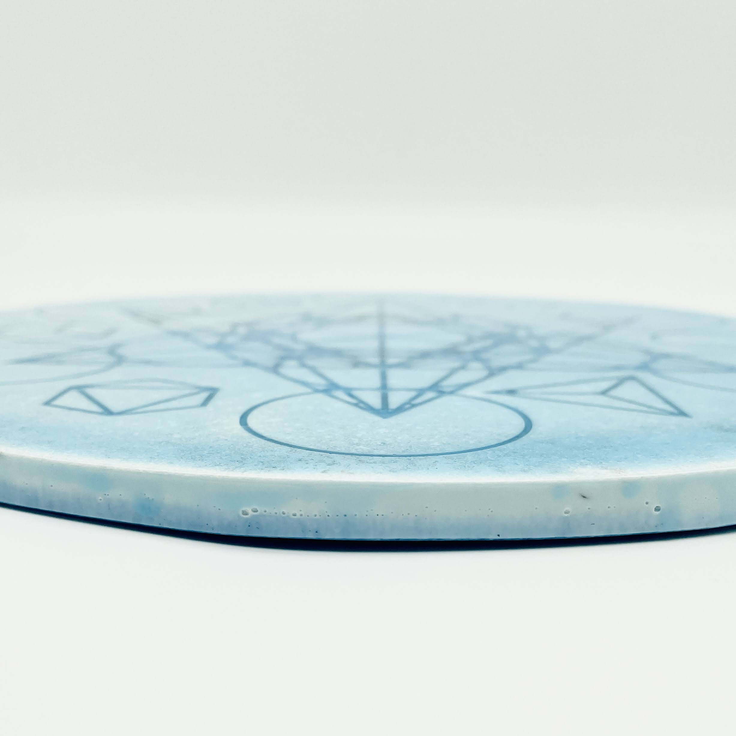 Runde blaue Orgonit-Scheibe mit geometrischem Muster auf weißem Hintergrund