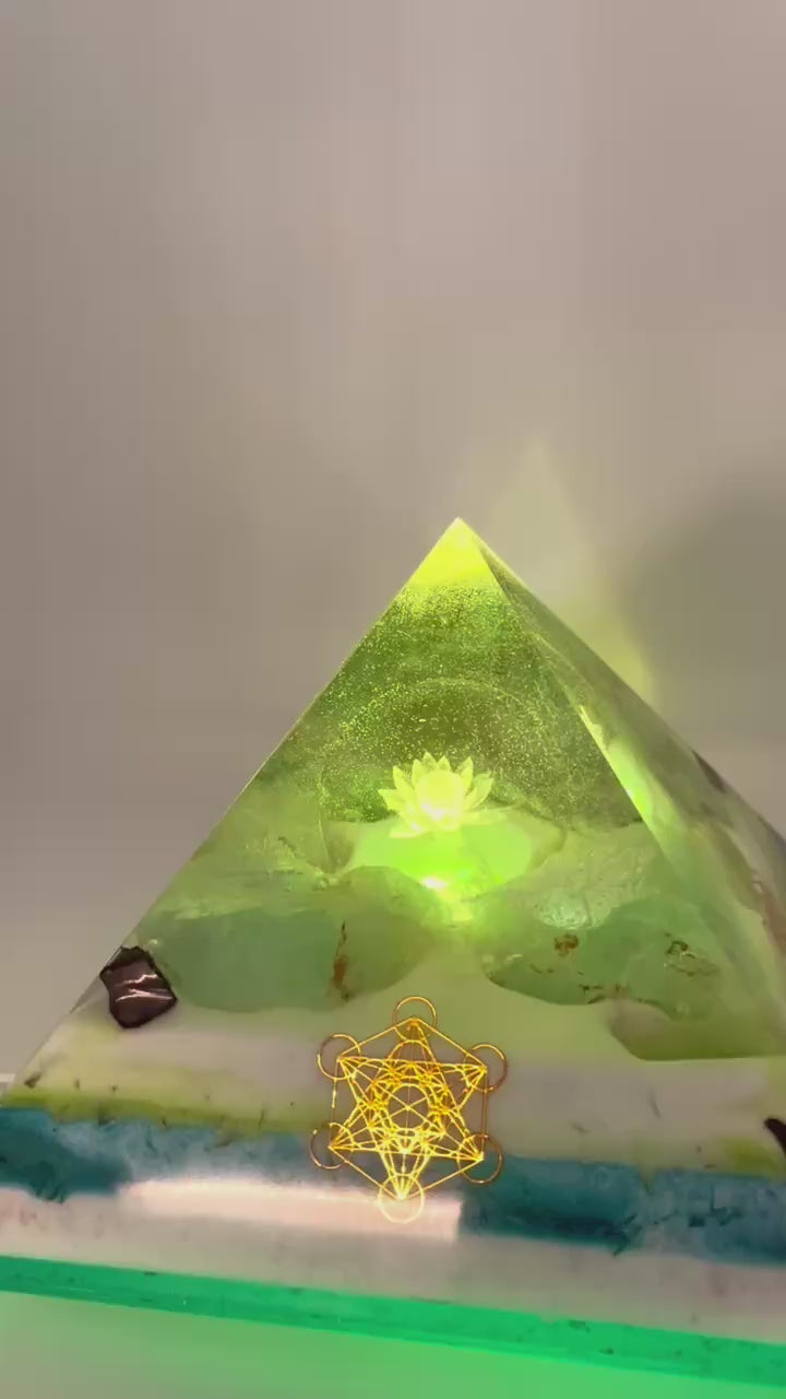 Orgonitpyramide mit beleuchteter Lotusblüte auf Holzsockel